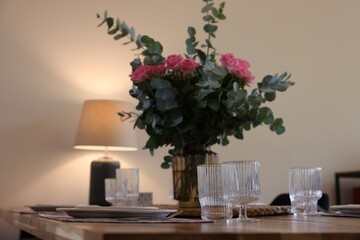 Beautiful table setting with bouquet indoors. Roses and eucalyptus branches in vase