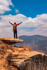 A hiker on a scenic view point at the top of mountain in Mbooni, Makueni County, Kenya