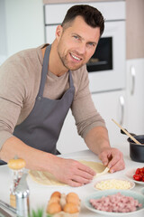 happy handsome man cooking in kitchen at home
