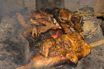 Photo of traditional Indonesian food, a rooster being grilled with billowing smoke