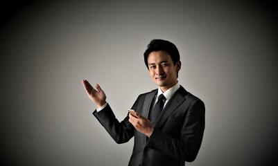 Obraz na płótnie Canvas 携帯を持つスーツを着た日本人ビジネスマン