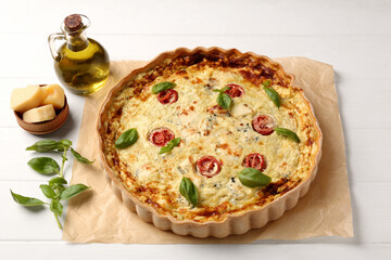 Delicious homemade cheese quiche and ingredients on white table