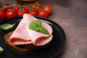 Delicious sandwich with ham on brown table, closeup