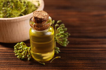 Bottle of essential oil and fresh dill on wooden table, closeup. Space for text