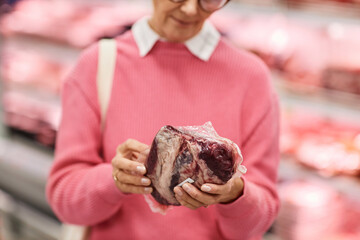 Close up of woman choosing fresh meat while shopping for groceries in supermarket, copy space