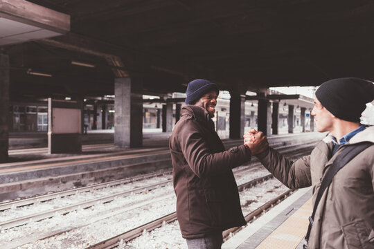 two men multiethnic freinds shaking hands smiling