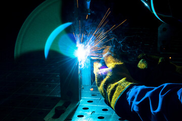 bright blue welding fire, on a dark background, hands in protective gloves, glare