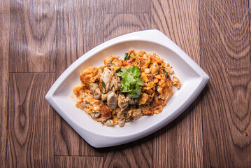 local traditional chinese stir wok fried big fresh oyster seafood with crispy chicken egg omelette in plate on wood table asian restaurant banquet cuisine halal food menu