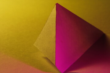 Papel para impresiones digitales en forma de un  tri&aacute;ngulo de color magenta y amarillo con  l&iacute;neas rectas geom&eacute;tricas y  sombra suave, presenta un dise&ntilde;o abstracto  con fondo amarillo en Bokeh
