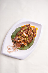 grilled bbq fresh whole seafood squid sooting octopus with spicy samba chilli sauce and petai smelly bean vegetables in banana leaf plate on wood table asian restaurant banquet cuisine halal food menu