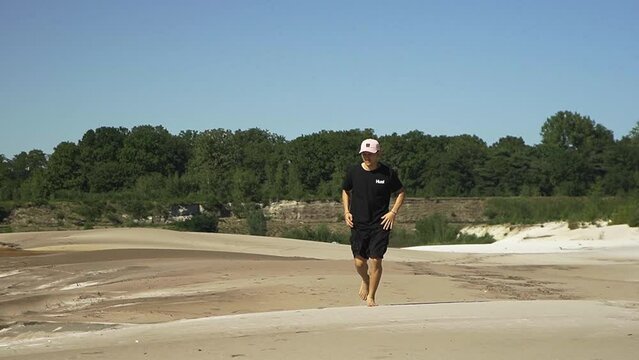 Young hispanic male running over sandy beach from a lake in the Belgian forest.