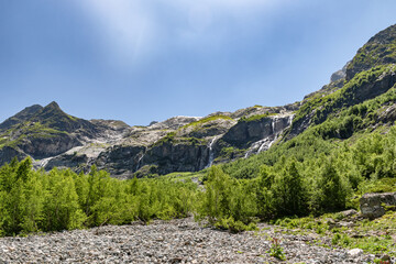 View of the valley of Sofia waterfalls with green mountain slopes, rocks and waterfalls