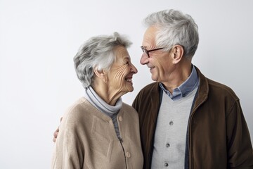mid-shot of a 90 year old couple smiling at each other, white background, authentic, happy