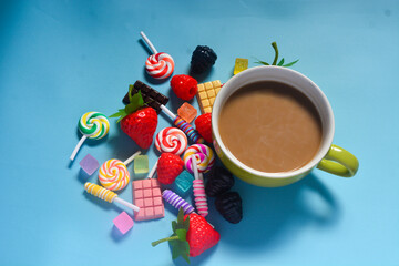Flat lay a cup of coffee and chocolate, candies and cotton candy as a frame
