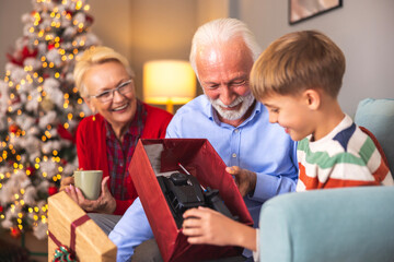 Obraz premium Grandparents giving Christmas present to their grandson