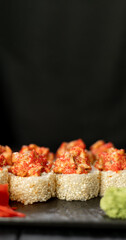 Baked volcano sushi on a black background, space for text. Japanese cuisine concept