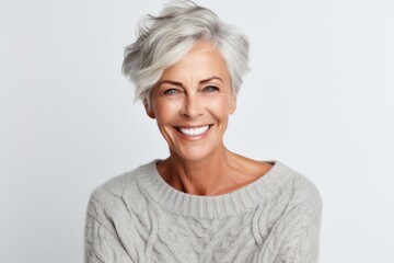 portrait of a Polish woman in her 60s wearing a cozy sweater against a white background