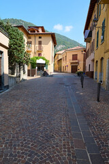 Fototapeta premium Italy, Lombardia, Canzo, narrow alley at historic old town, against the background of Italian Alps. Street scene. Tourism. Adventure. Trip. Travel destination. Vertical photography