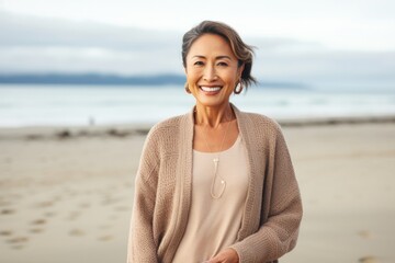 Fototapeta na wymiar portrait of a confident Filipino woman in her 40s wearing a chic cardigan against a beach background