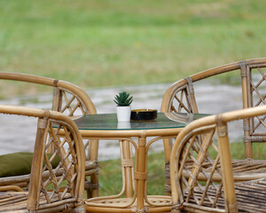 Selective focus photo of an empty ashtray and plant decoration on a table in between wooden wicker...