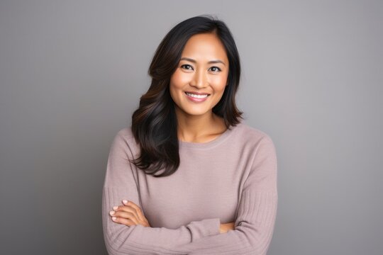 portrait of a confident Filipino woman in her 30s wearing a cozy sweater against a minimalist or empty room background
