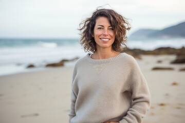 portrait of a confident Israeli woman in her 40s wearing a cozy sweater against a beach background