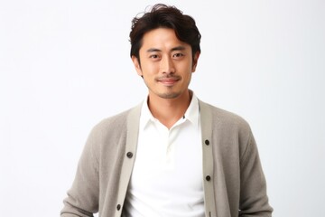 portrait of a confident Japanese man in his 30s wearing a chic cardigan against a white background