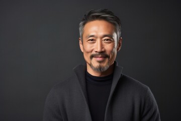 Fototapeta premium portrait of a confident Japanese man in his 40s wearing a chic cardigan against an abstract background