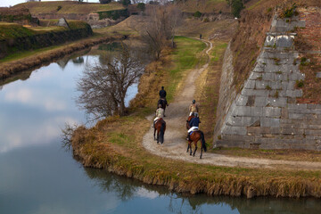 Horseback riders gracefully explore Palmanova's bastions - obrazy, fototapety, plakaty