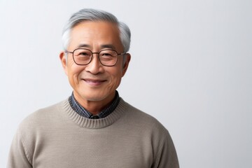 Obraz premium portrait of a confident Japanese man in his 70s wearing a chic cardigan against a white background