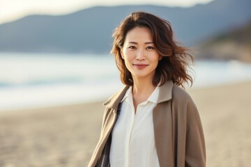 portrait of a confident Japanese woman in her 30s wearing a chic cardigan against a beach background