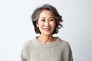 portrait of a confident Japanese woman in her 50s wearing a cozy sweater against a white background