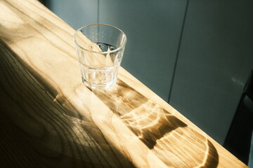 A crystal glass on a tabletop in a coffee shop, with the sun's rays shining through it