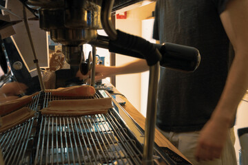 A close-up of the heart of a small cafe — an espresso machine while a barista taking orders in the background. The coffee machine stands as the focal point