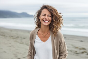 Portrait of a happy Polish woman in her 30s wearing a chic cardigan against a beach background
