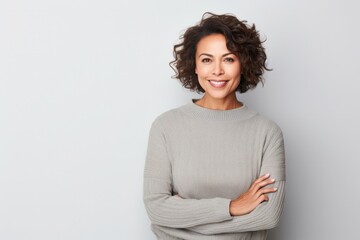 portrait of a confident Mexican woman in her 40s wearing a cozy sweater against a minimalist or empty room background