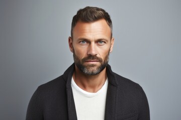Fototapeta premium portrait of a serious, Polish man in his 30s wearing a chic cardigan against a white background
