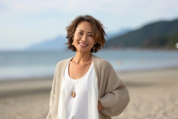 Portrait of a Japanese woman in her 40s wearing a chic cardigan against a beach background
