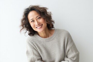 Portrait of a Japanese woman in her 30s wearing a cozy sweater against a white background