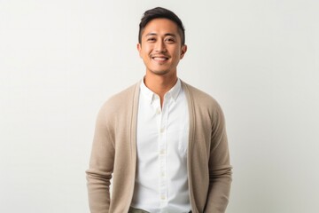 Fototapeta premium Portrait of a confident Filipino man in his 30s wearing a chic cardigan against a white background