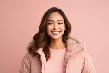 Fototapeta premium Portrait of a confident Filipino woman in her 30s wearing a warm parka against a pastel or soft colors background