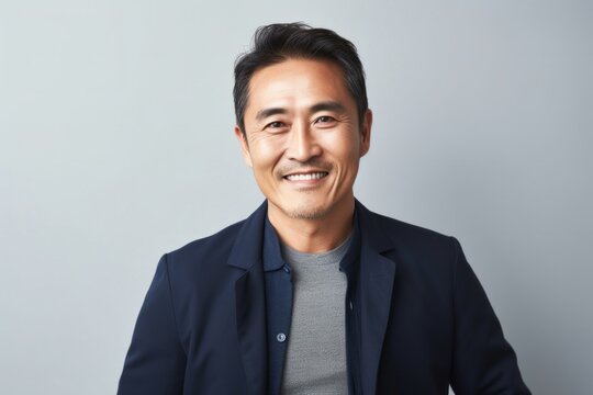 Portrait of a confident Japanese man in his 40s wearing a chic cardigan against a minimalist or empty room background