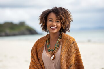 Portrait of a confident Kenyan woman in her 30s wearing a chic cardigan against a beach background