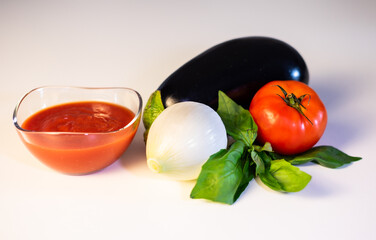 Ingredients on white table for making Italian pasta alla norma, traditional recipe with tomato, eggplant and onion. Healthy eating, Mediterranean diet
