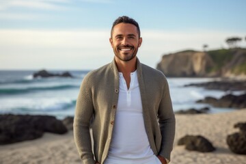 Portrait of a confident Mexican man in his 30s wearing a chic cardigan against a beach background