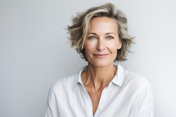 Portrait of a serious, Polish woman in her 50s wearing knee-length shorts against a white background