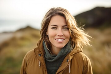 Portrait of a Polish woman in her 30s wearing a warm parka against a beach background