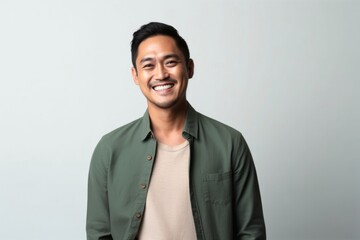 medium shot portrait of a happy Filipino man in his 30s wearing a chic cardigan against a minimalist or empty room background - obrazy, fototapety, plakaty