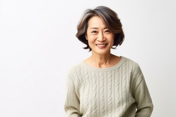 Fototapeta premium medium shot portrait of a Japanese woman in her 50s wearing a cozy sweater against a white background