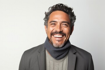 portrait of a happy Mexican man in his 40s wearing a chic cardigan against a white background